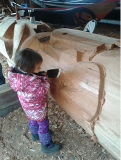 Petite fille sculptant un poteau totémique.