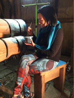 Une femme assise peint un poteau totémique.