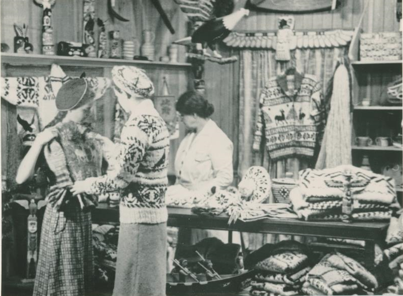 Women inside of a store looking at Cowichan sweaters and carvings.