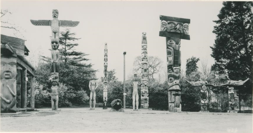Plusieurs figures humaines debout au Parc Thunderbird avec d’autres poteaux et figures sculptés .