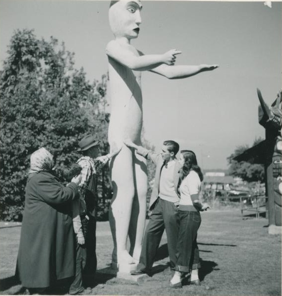 Groupe de personnes regardant et touchant une des figures humaines sculptées au Parc Thunderbird.