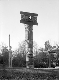 Mortuary pole in Thunderbird Park surrounded by poles