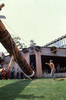 Des personnes regardent l'élévation du poteau devant l'atelier de sculpture.