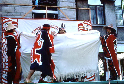 Dancers holding a blanket and dancing on stage.