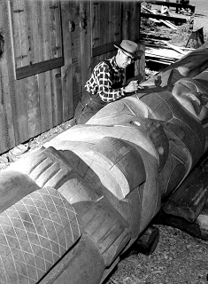 Homme sculptant une réplique de poteau dans un atelier.