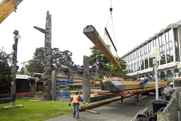 Beams of the Carving Studio being lifted up and onto a truck bed by a crane.