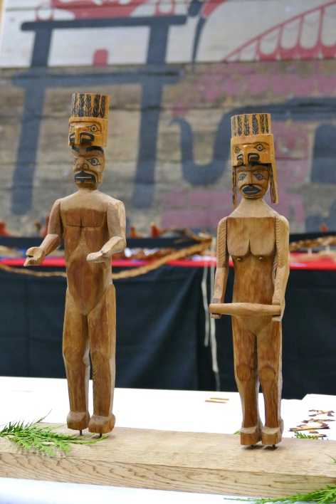 Detail of small carved human welcome figures standing on a table.