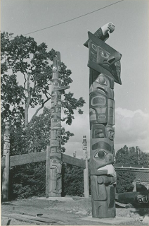 Mortuary pole in Thunderbird Park surrounded by poles