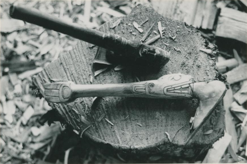 Deux outils de sculpture au-dessus d’un tronc, dont un avec une poignée sculptée.