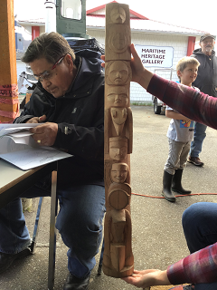Small totem pole beside a man reading a book