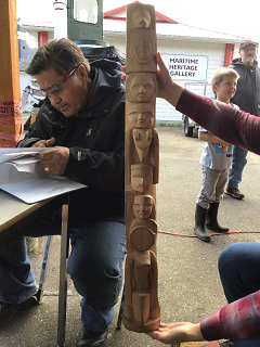 Petit totem à côté d'un homme qui lit un livre.