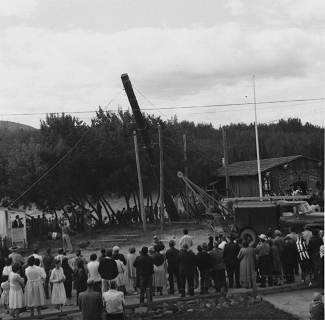 Crowd of people watching a totem pole raising