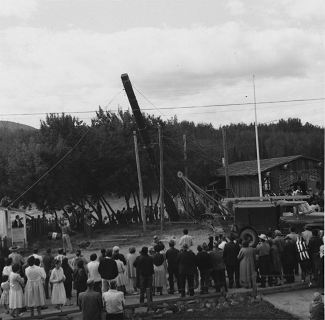 Foule de personnes assistant à l'élévation d'un totem.