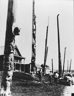 Group of totem poles in front of a house