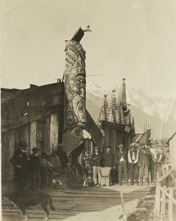 Personnes debout devant un totem avec l'entrée dans la bouche du totem.