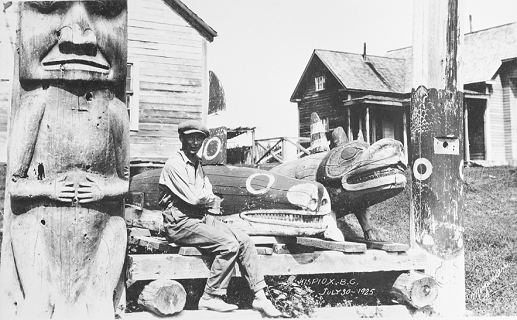 Man sits amongst totem poles