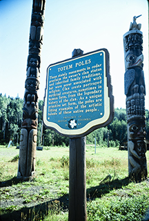 Plaque standing in front of totem poles